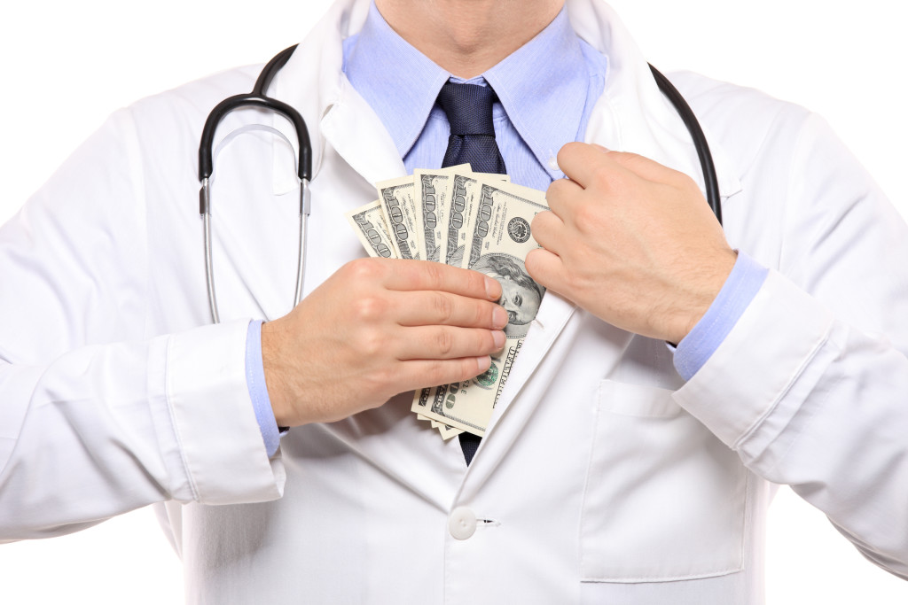 A doctor putting money in his pocket isolated on white background