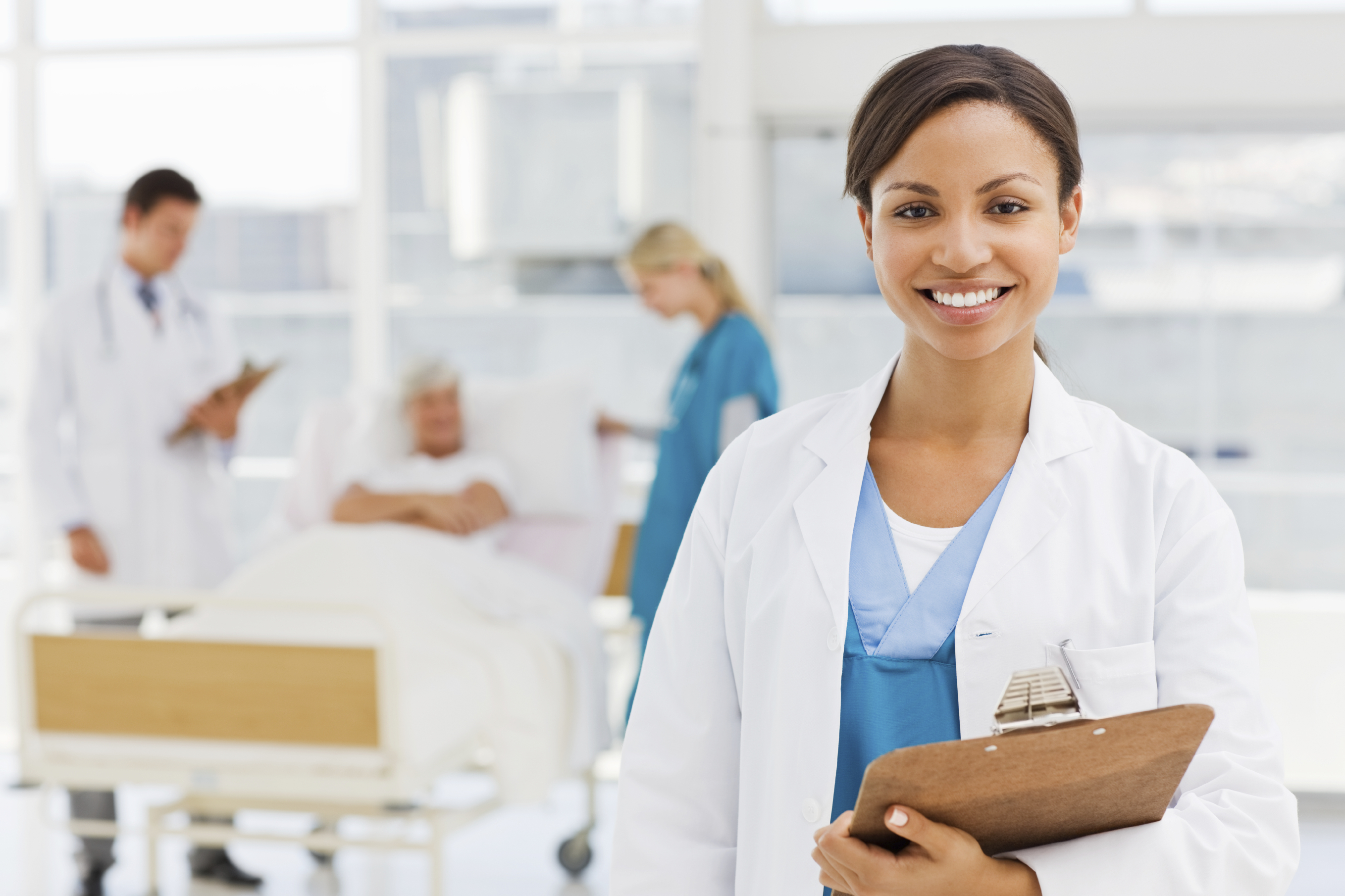 Smiling beautiful doctor holding report while colleagues talking to patient in background